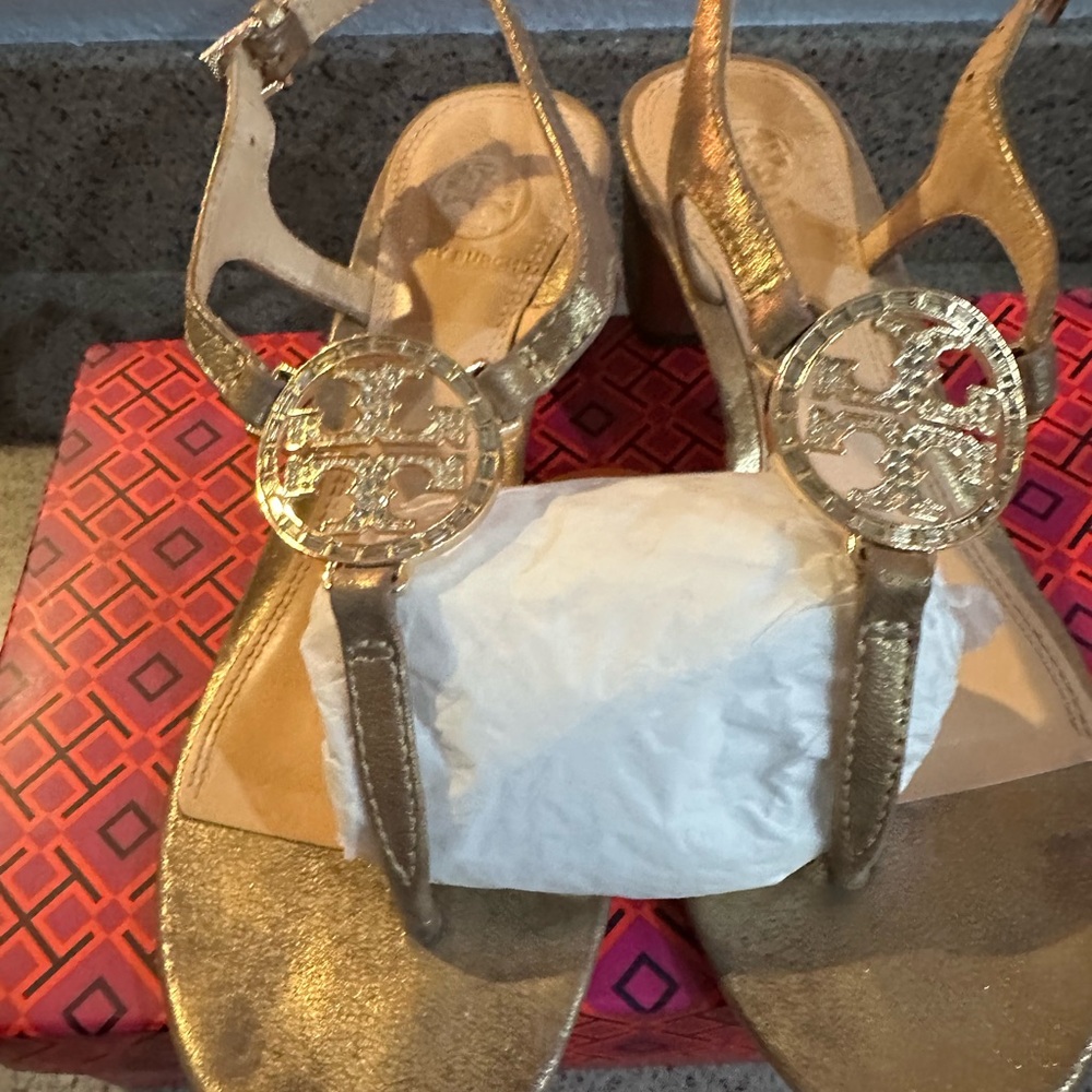 Well worn Tory Burch gold sandals with rhinestone emblem.